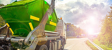 Lastkraftwagen fährt auf einer Landstraße mit Blick auf eine grüne Landschaft.