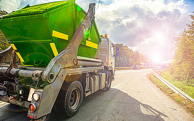 Lastkraftwagen fährt auf einer Landstraße mit Blick auf eine grüne Landschaft.