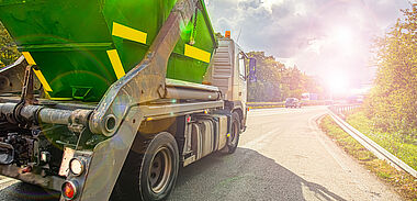 Lastkraftwagen fährt auf einer kurvigen Landstraße mit Blick auf eine grüne Landschaft.